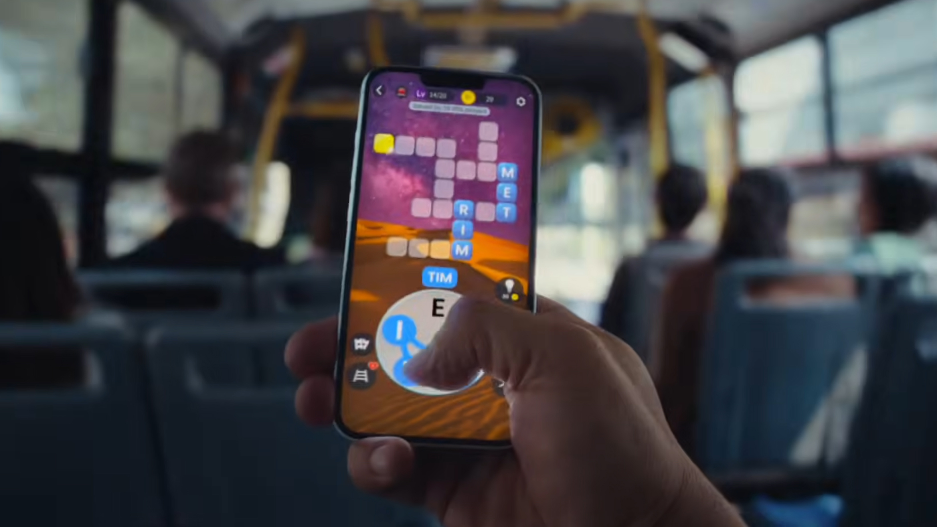A hand holding iPhone 17e on a bus and playing