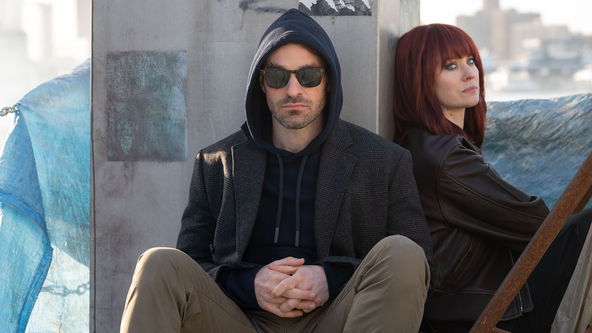 Matt with sunglasses and his hood up and a red-haired Karen sitting next to each other in Daredevil: Born Again season 2
