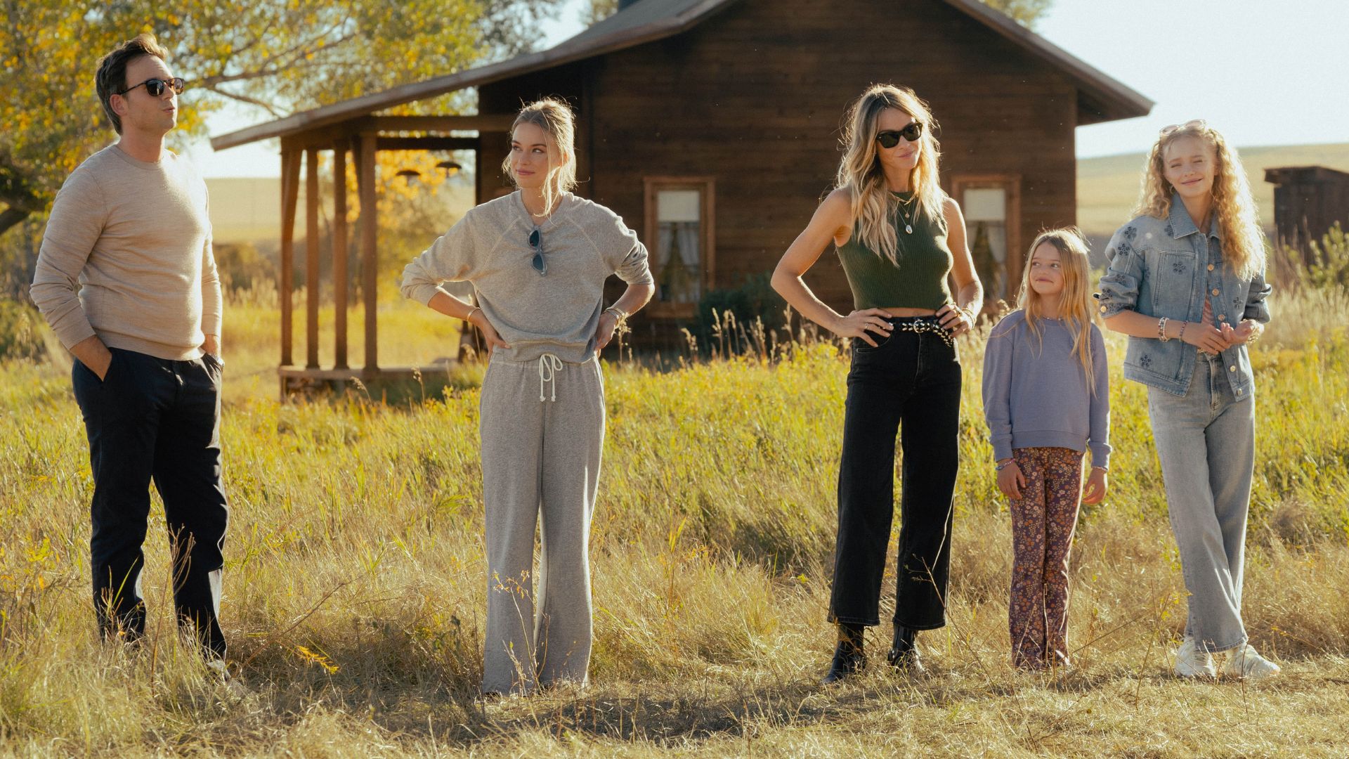 A line of people in a field with their hands on their hips.