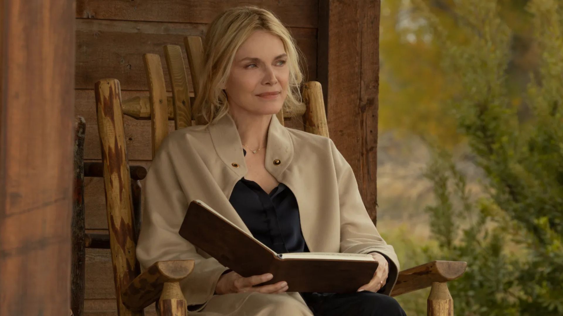 Michelle Pfeiffer sitting in a rocking chair holding a book