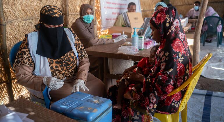 A woman holds a child while receiving medical care at a UNICEF-supported health center in Sudan's Kordofan region, where families have fled violence.