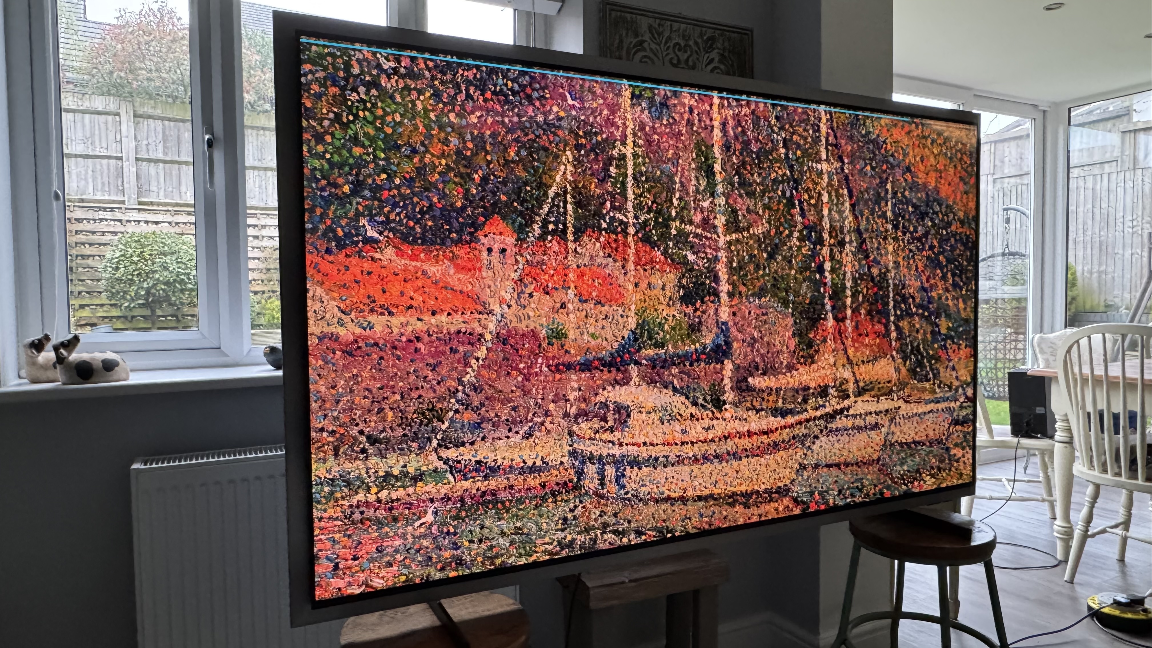 The Samsung S99H/S95H TV in a home, showing the artwork of a ship on the screen in an impressionist style