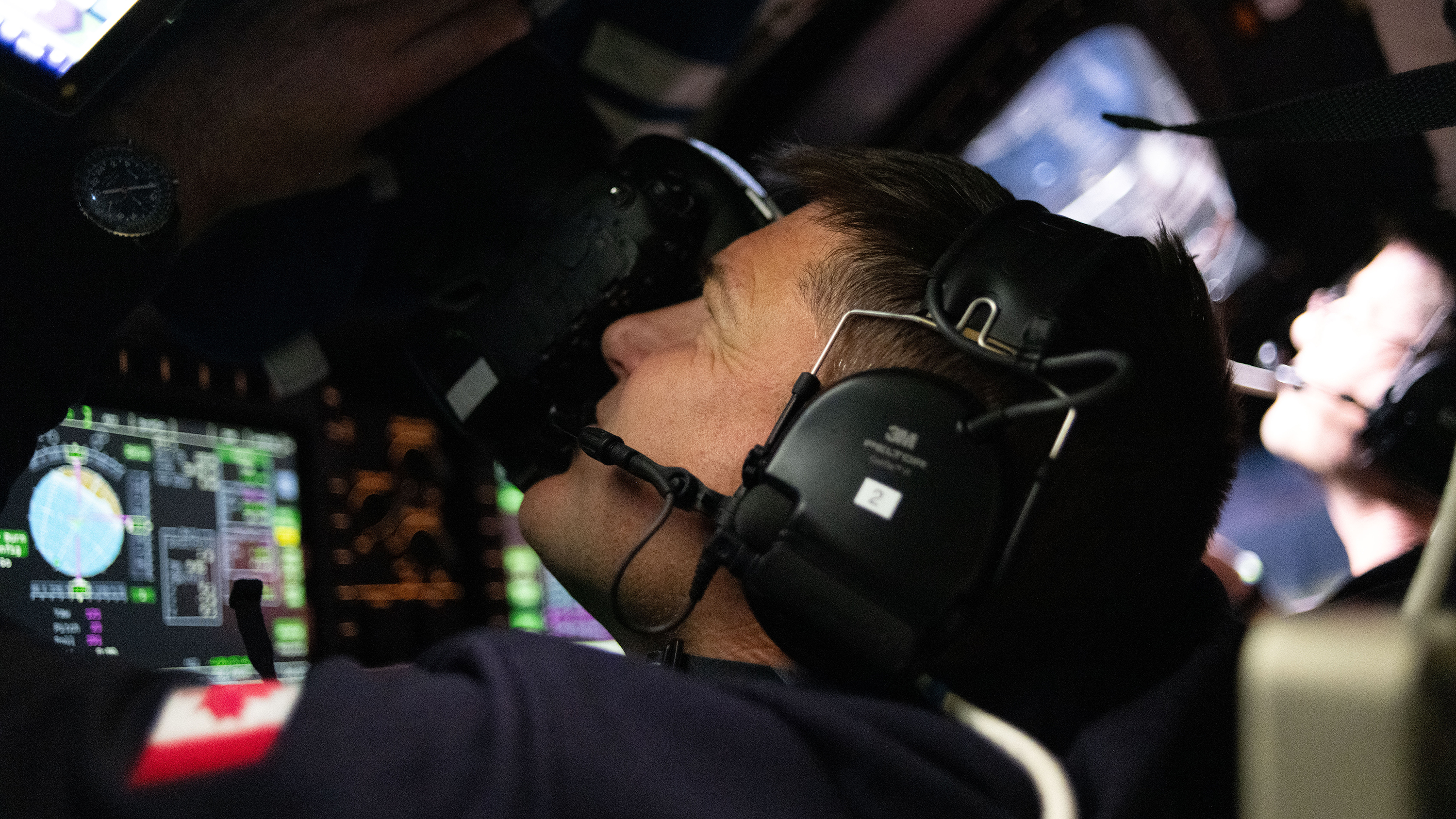 An Artemis II astronaut taking photographs through the spacecraft window.