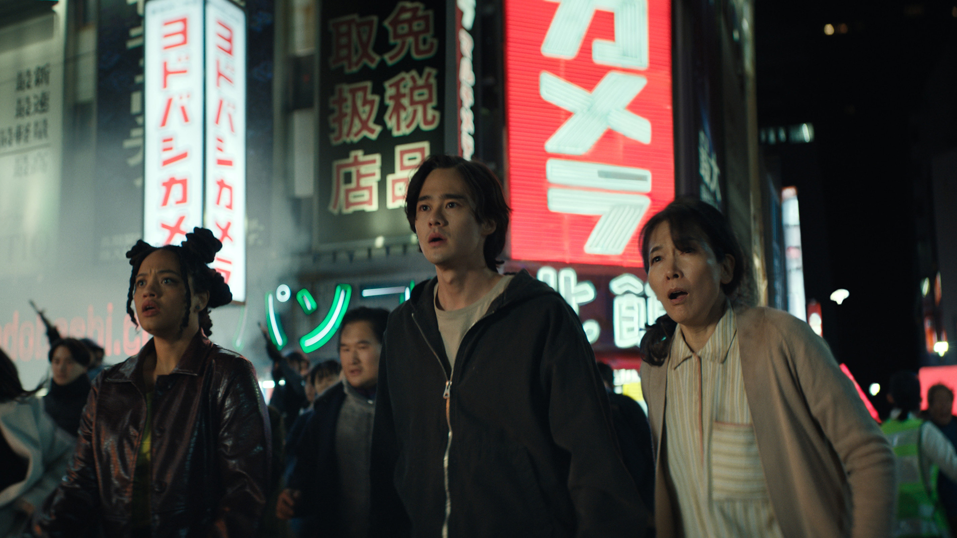 May and Kentaro standing on a crowded street at night and looking surprised in Monarch: Legacy of Monsters season 2, episode 6