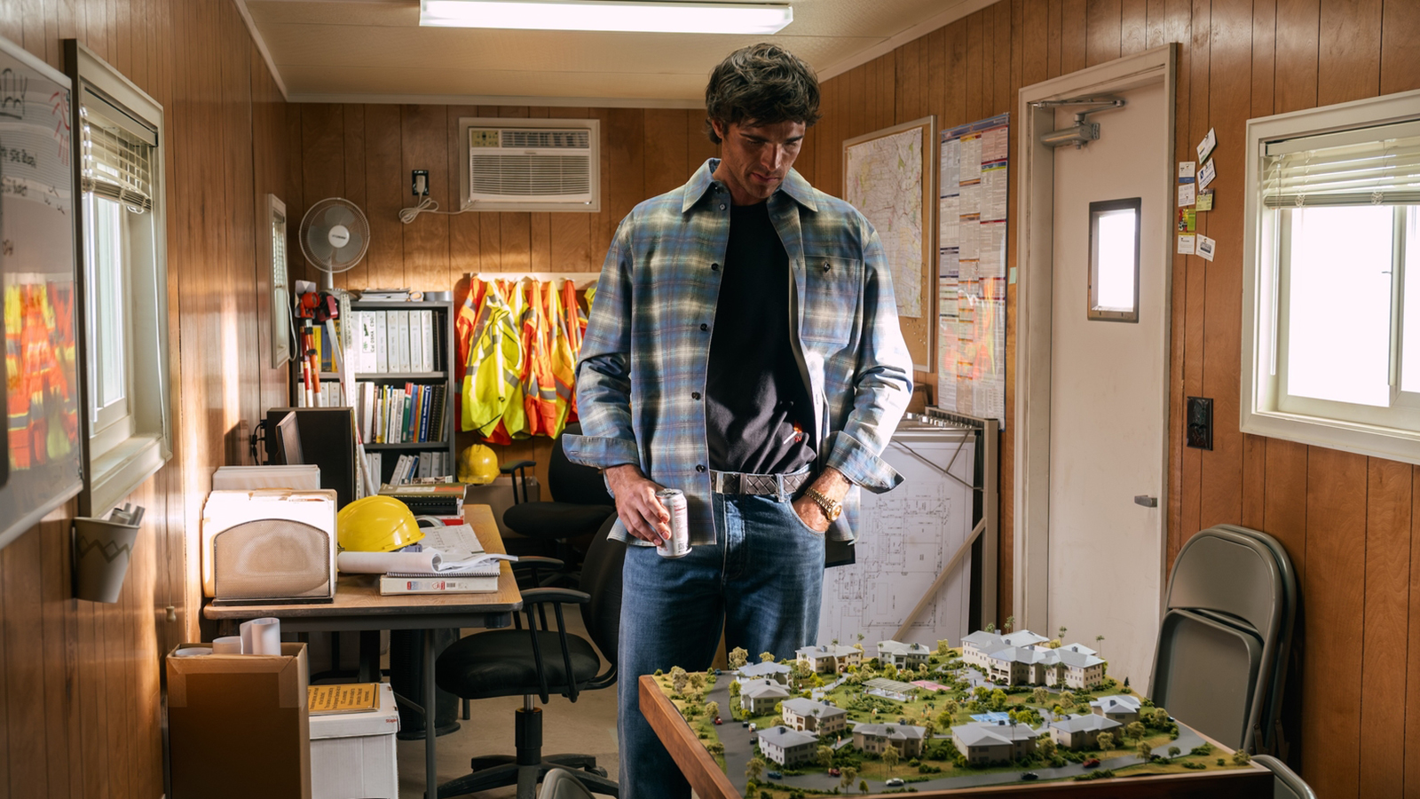 Nate looking at a scale model while holding a mug in season 3 of Euphoria