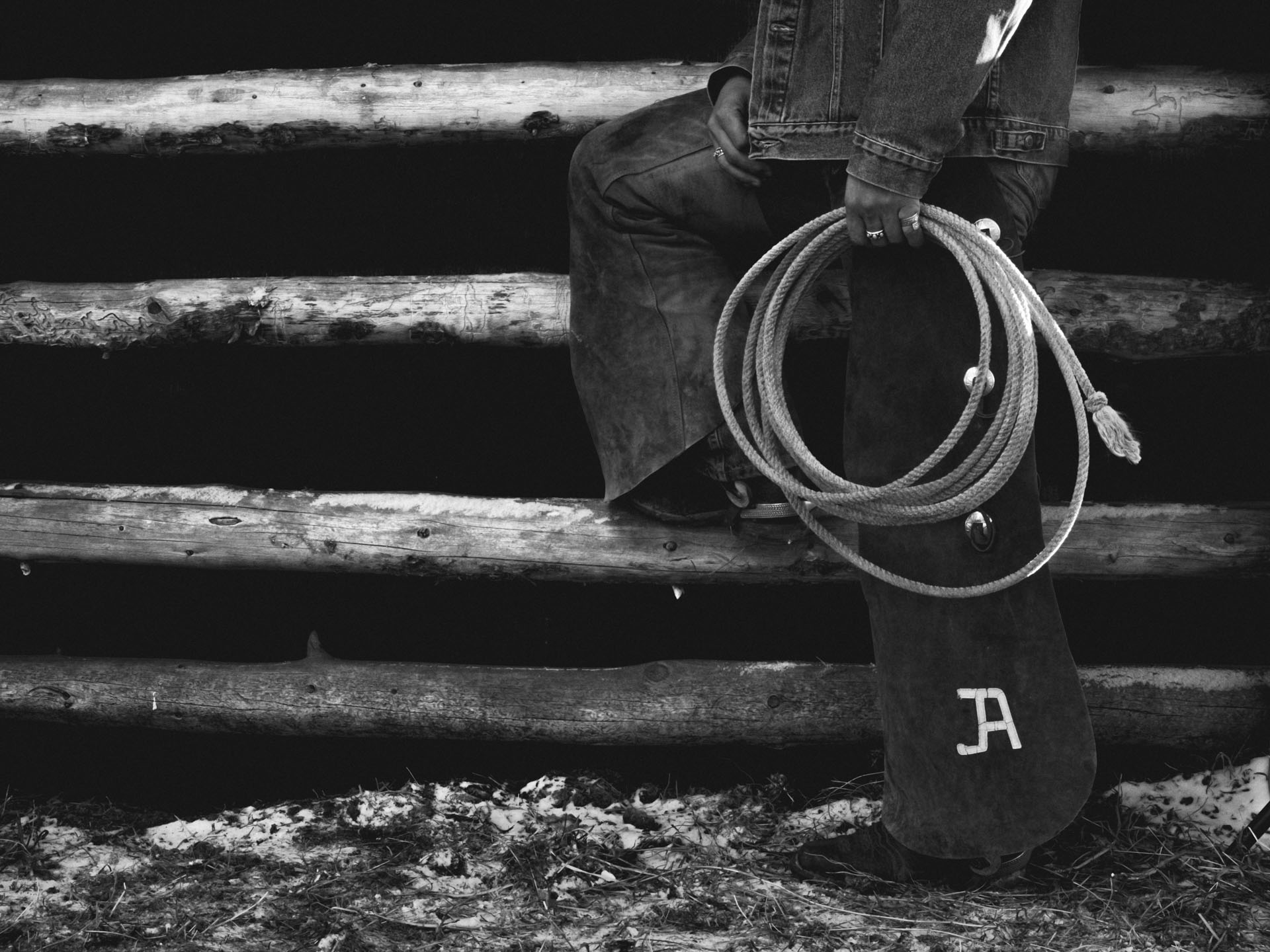Black and white image of the legs of a cowboy model, attached to a rope.
