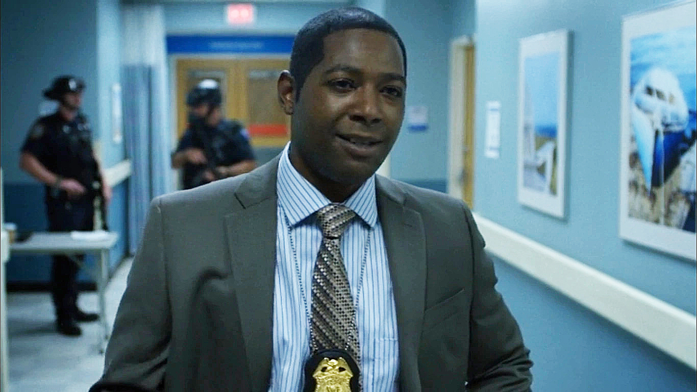 Brett Mahoney in a suit and his NYPD badge around his neck in the Netflix TV show Daredevil