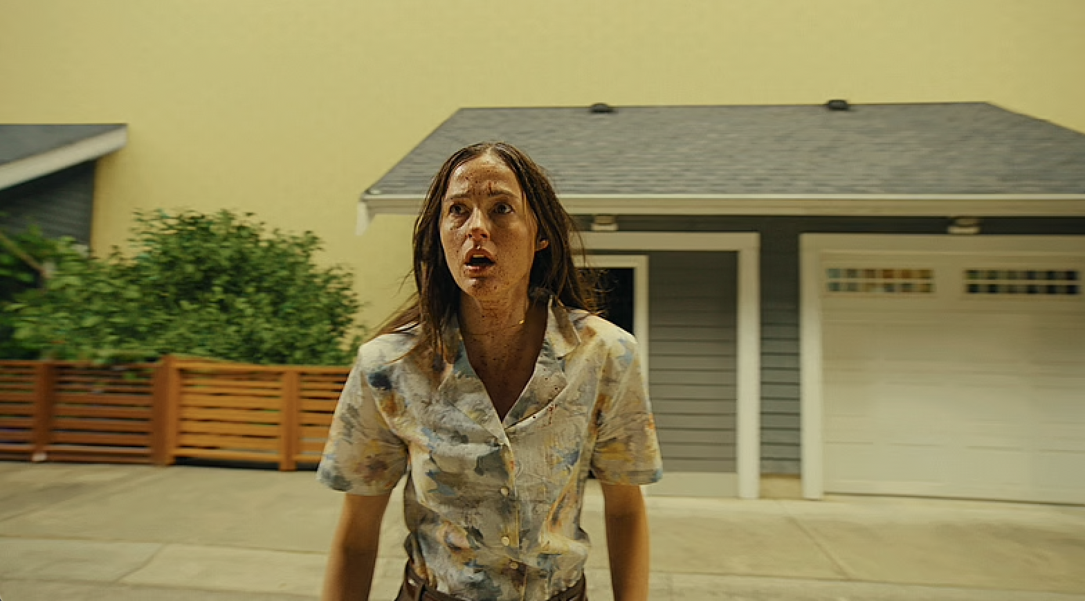 Renate Reinsve in Backrooms, standing in front of houses with a sickly yellow background behind them.