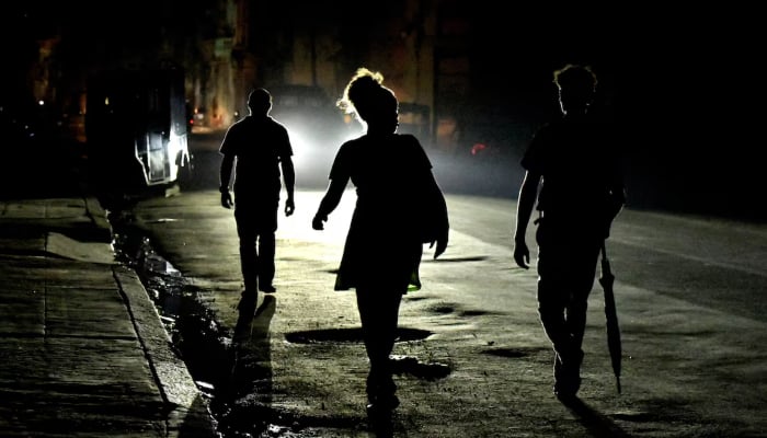 People walk on the street at night as Cuba suffers an island-wide blackout, in Havana, Cuba, on October 18, 2024. – Reuters