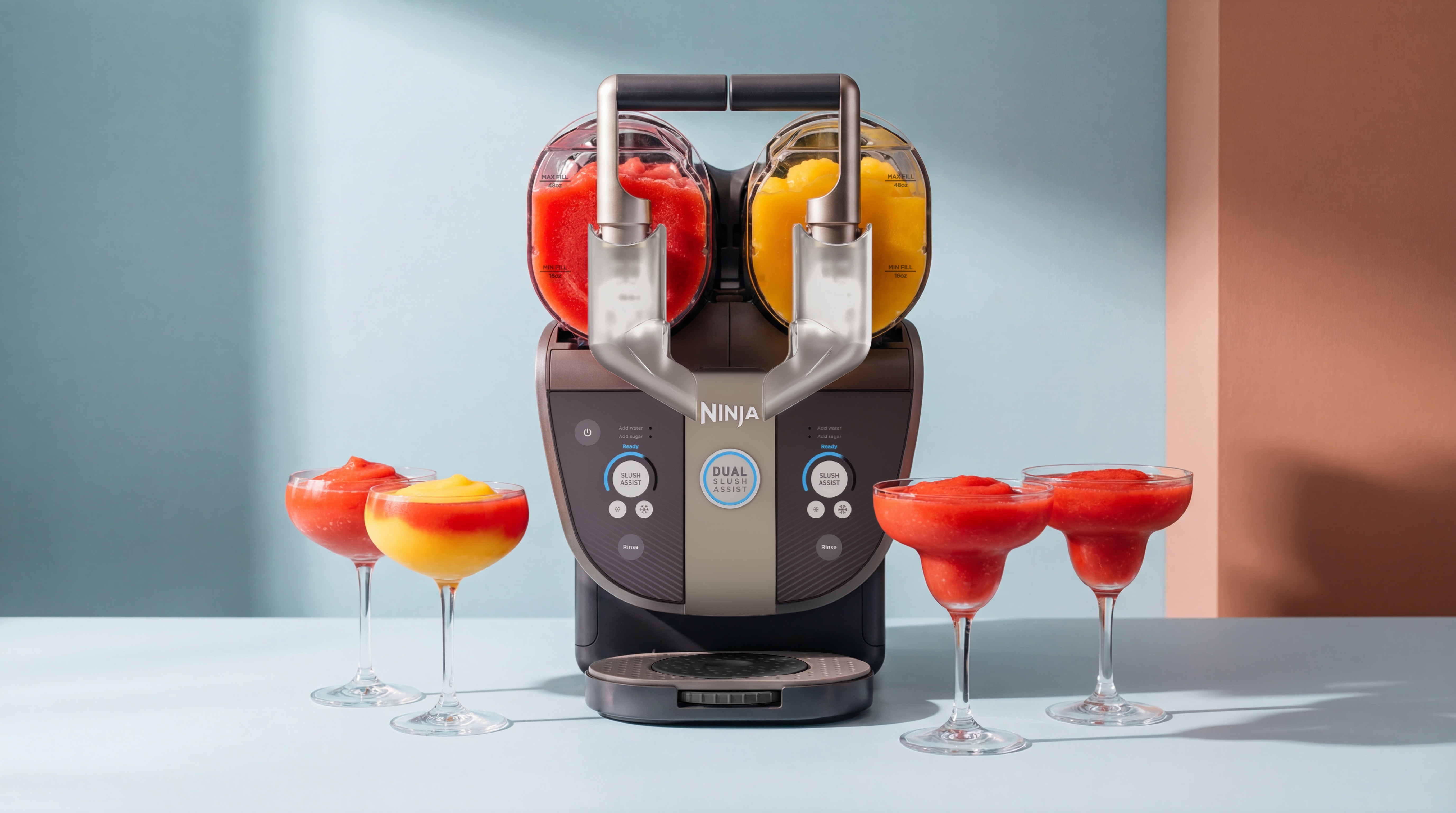 Ninja Slushi Twist on a light colored countertop with a red drink in one chamber and a yellow one in the second. In front are four brightly colored drinks in cocktail glasses.