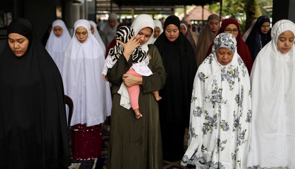 A Muslim woman carries a small child as she performs mass Eid ul Adha prayers at a mosque in Ampang, Malaysia, May 27, 2026. – Reuters