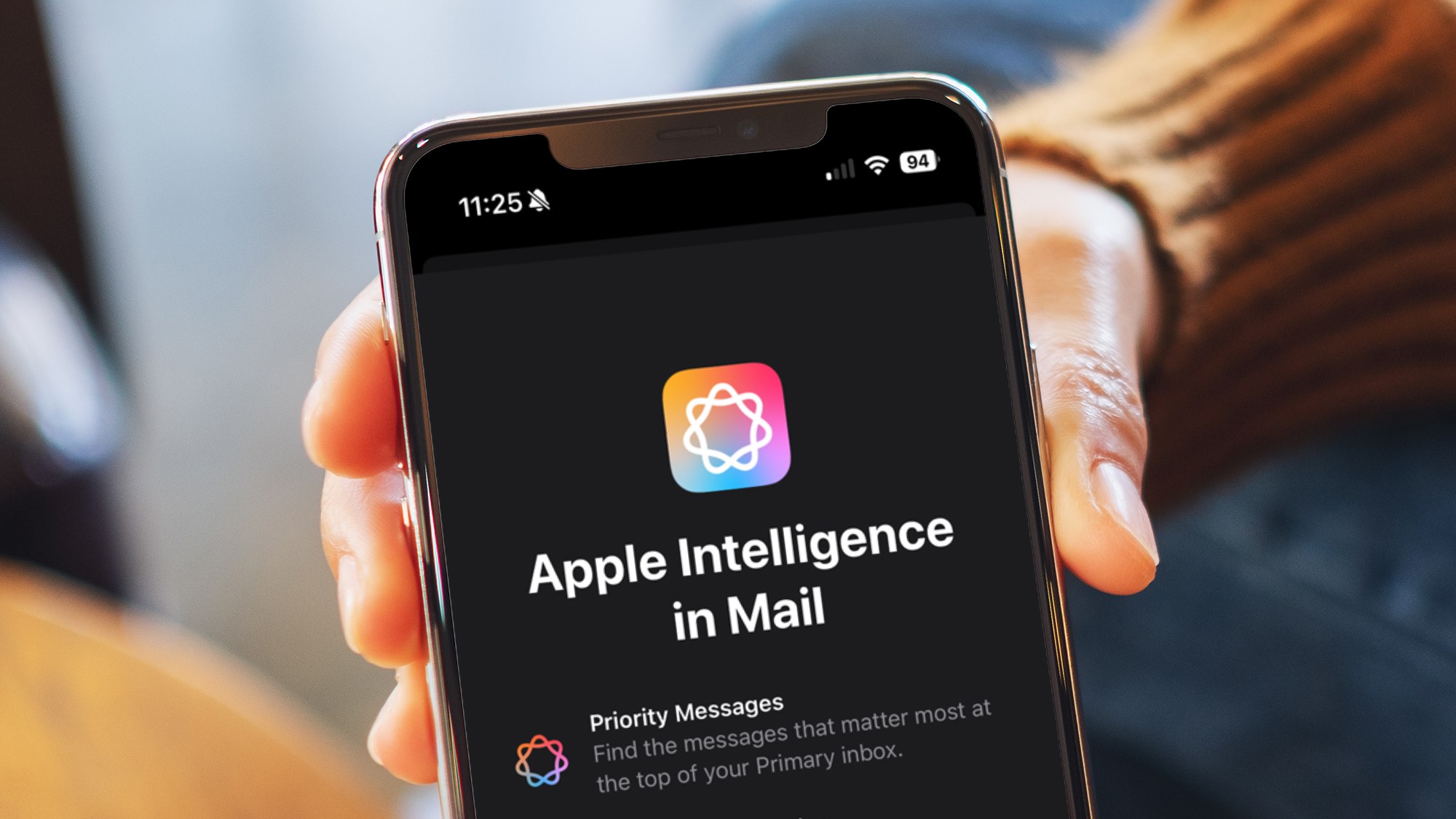 A hand holding an iPhone showing a guide to the new Apple Intelligence features in the Mail app