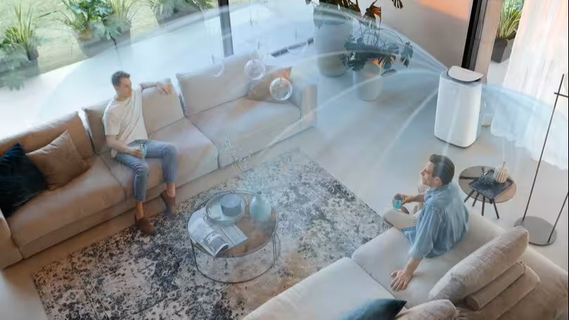 De'Longhi air conditioning in a room with two people and lines representing air movement.