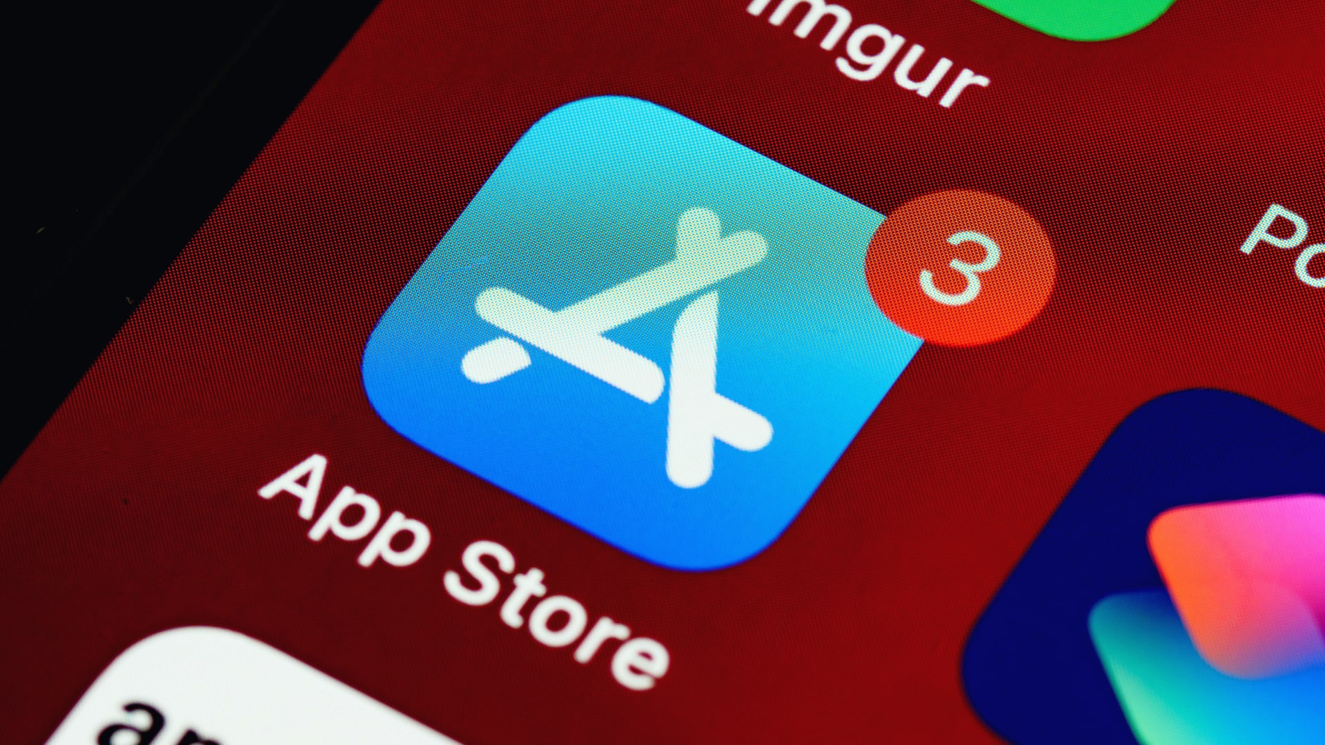 A close-up photo of an iPhone, with the App Store icon highlighted in the center of the image.