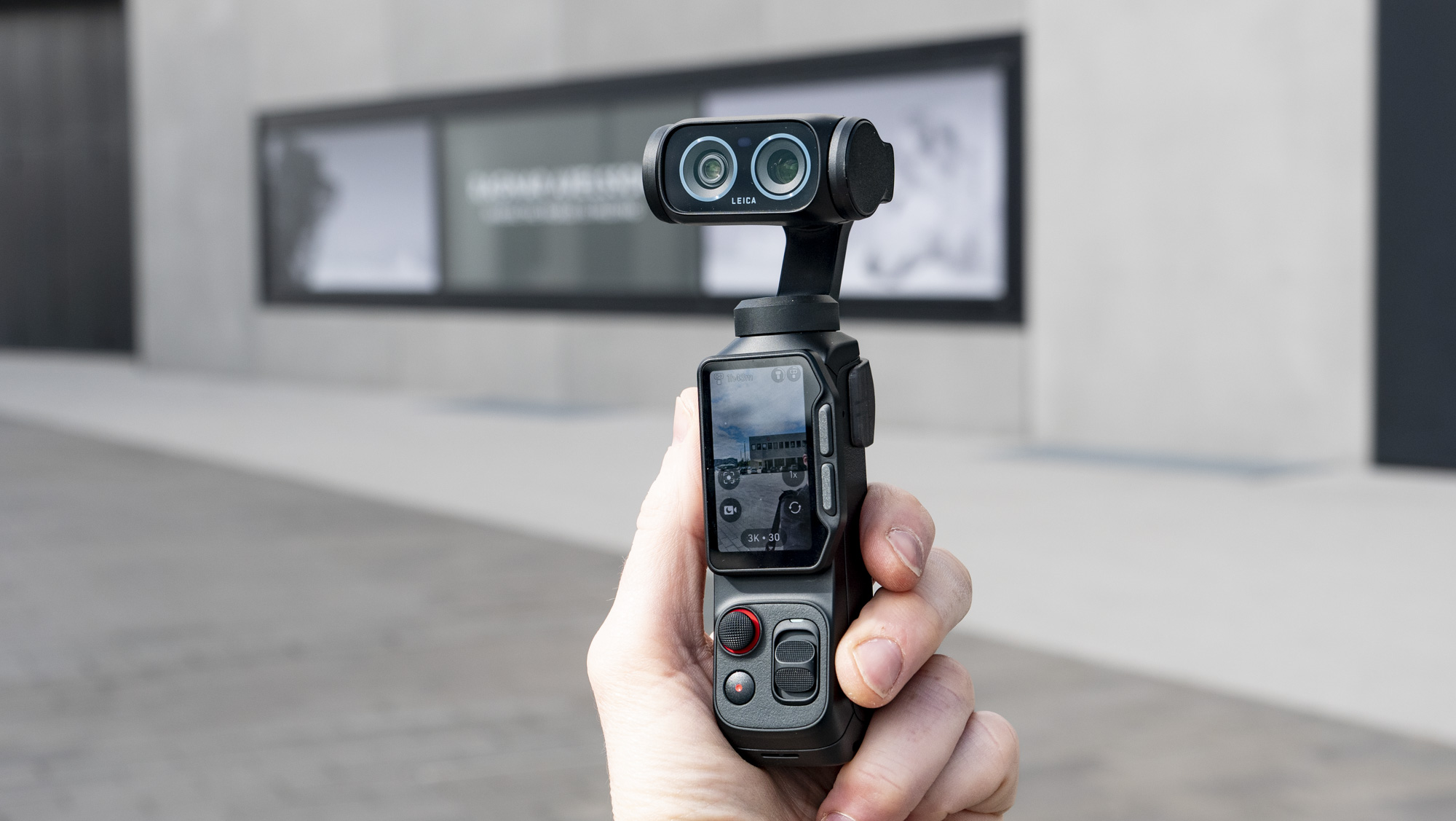 Insta360 Luna Ultra vlogging camera in hand, outdoors in a gray urban scene