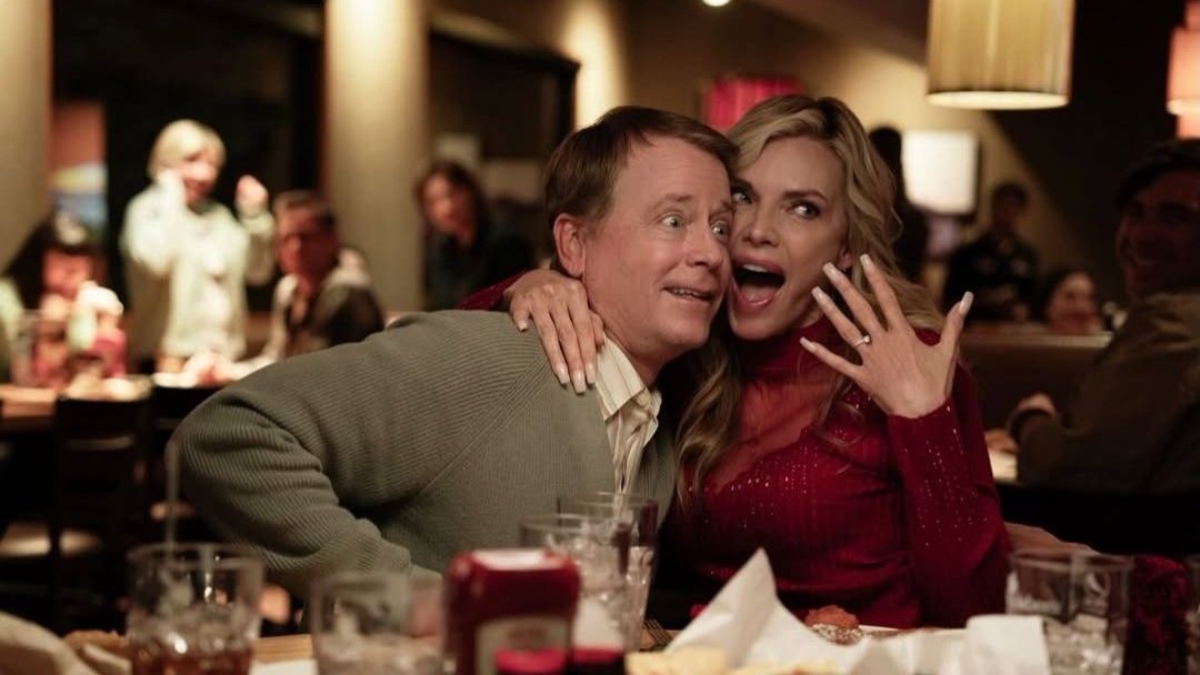 Greg Kinnear and Michelle Pfieffer in Margo's Got Money Troubles. Pfieffer's character enthusiastically shows off her engagement ring.