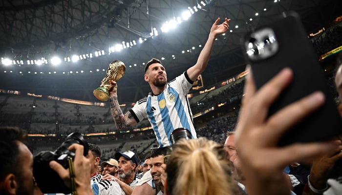 Argentine captain and striker #10 Lionel Messi (right) holds the FIFA World Cup Trophy after the trophy ceremony after Argentina won the Qatar 2022 World Cup final between Argentina and France at the Lusail Stadium in Lusail, north of Doha, on December 18, 2022. – AFP