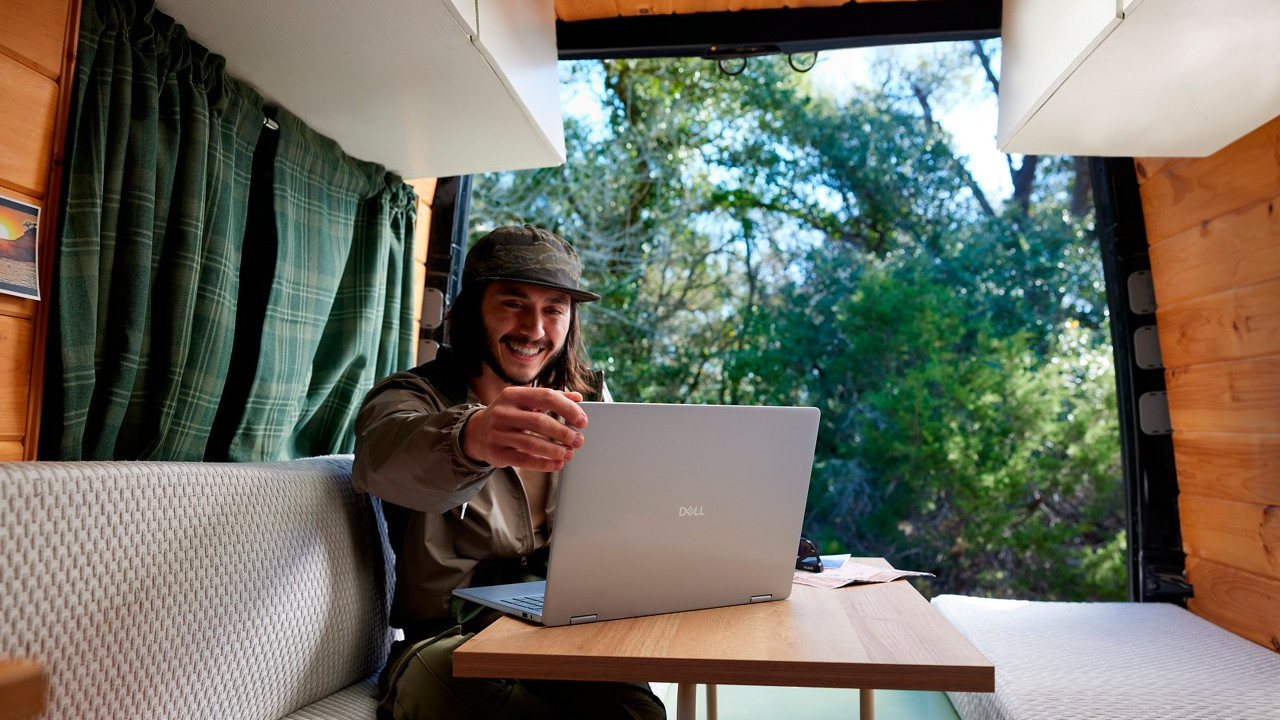Dell laptop running Windows 11 on a desk with a happy person looking at the screen
