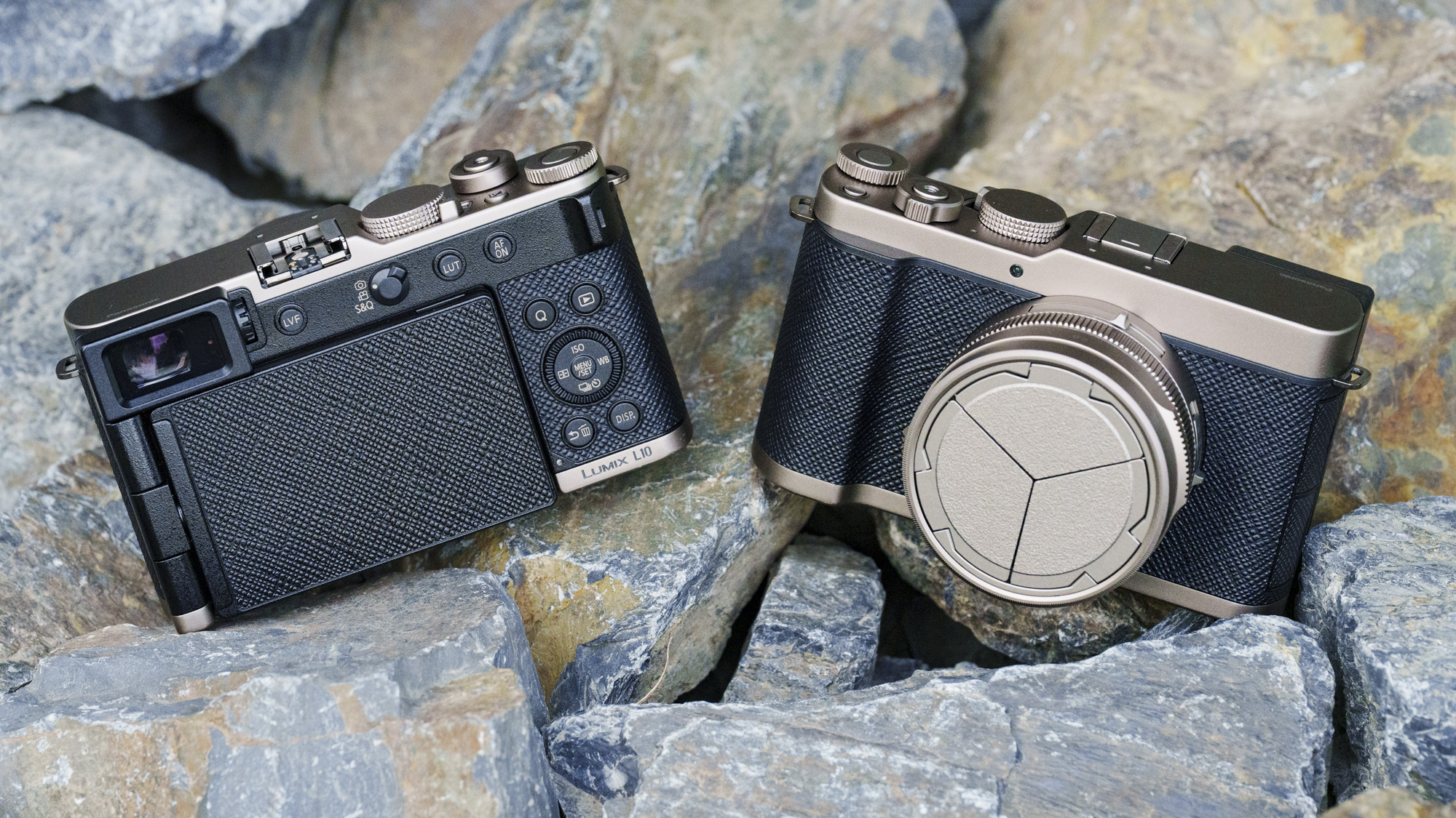 The special Gold Titanium edition of the Panasonic Lumix L10 compact camera, sitting on gray and rust-colored rocks