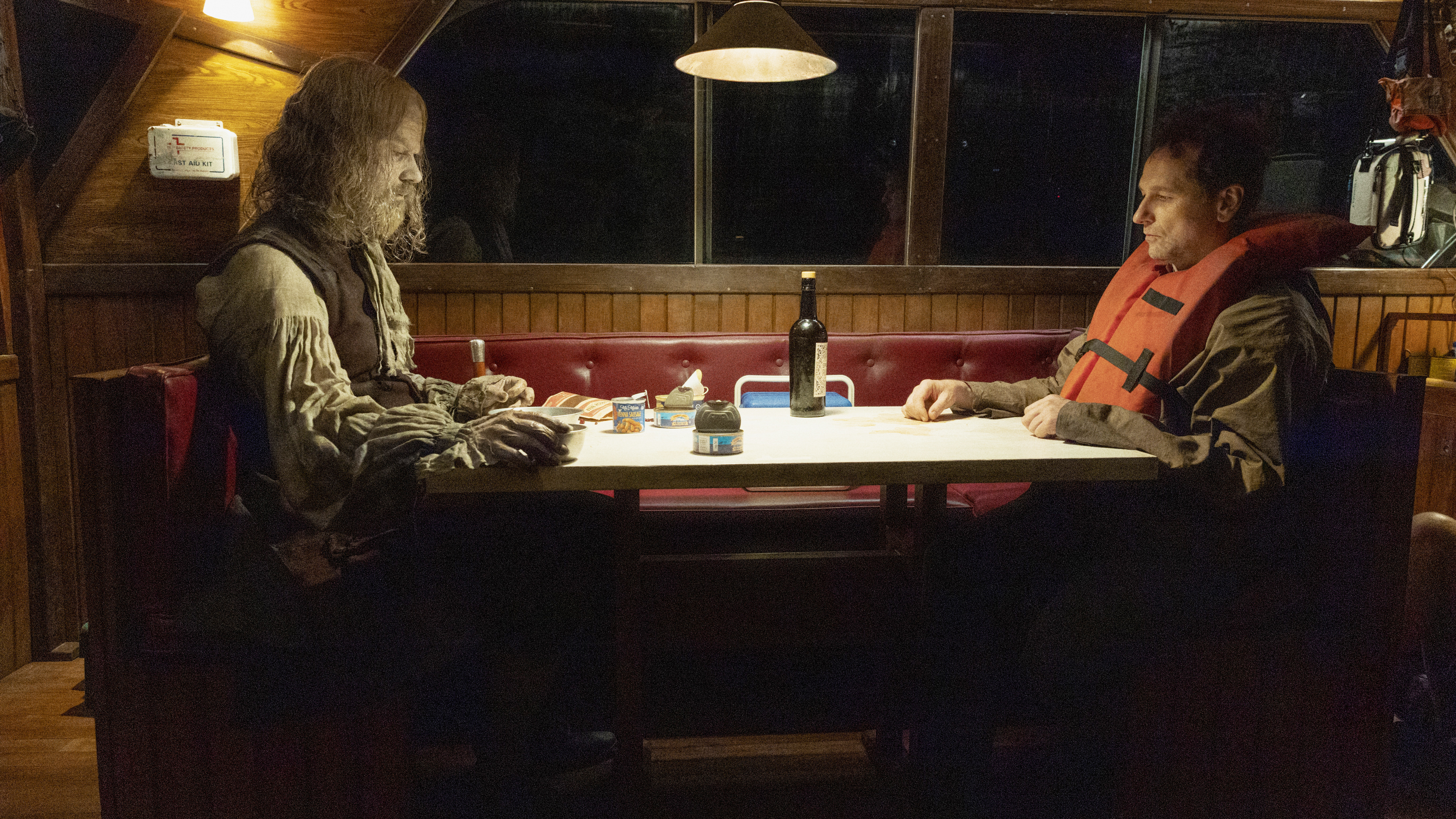 A zombified Richard Warren sits across from Tom Loftis on a boat at night in episode 7 of Widow's Bay.