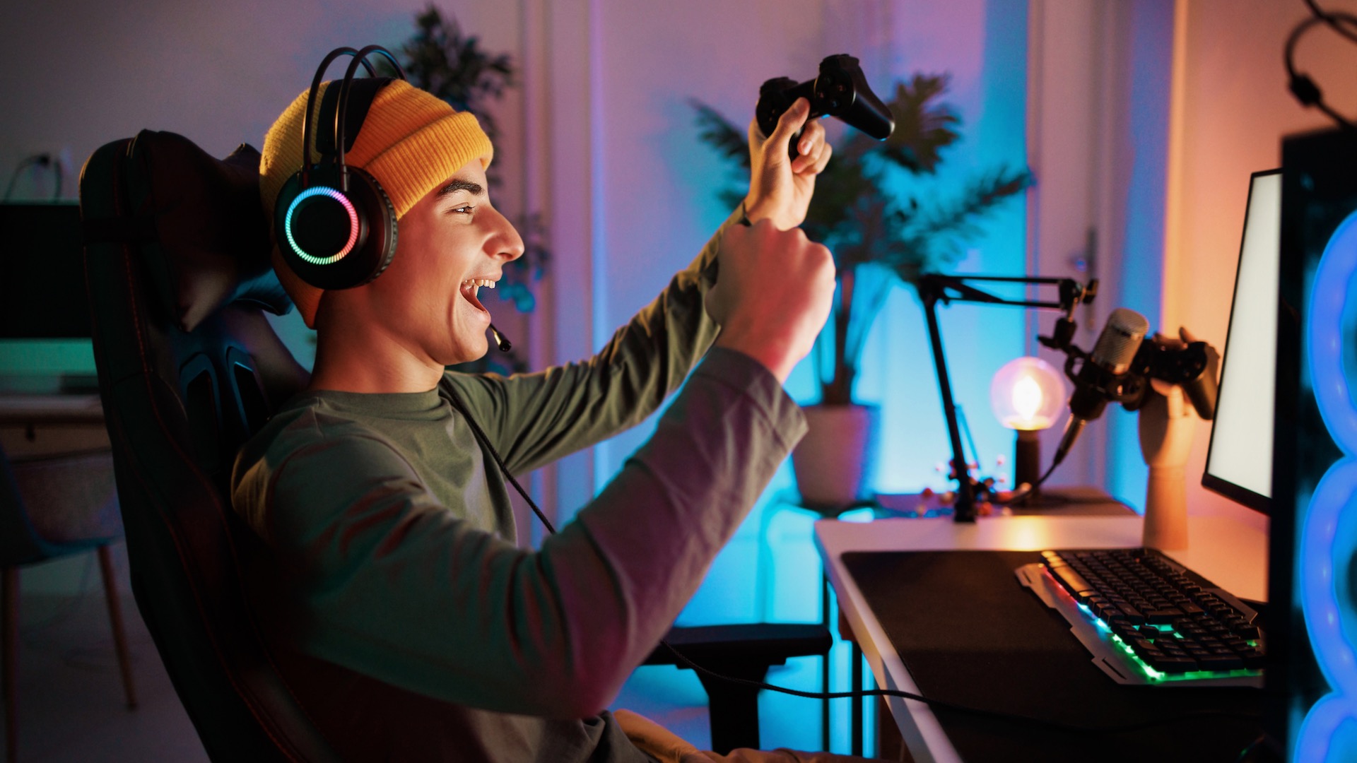 A young teenager plays a PC game and celebrates a victory.