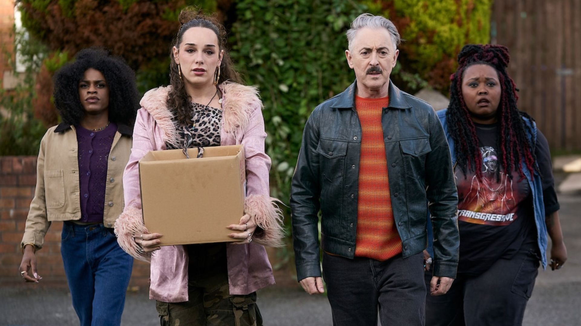 A group of four people walk in the middle of a street.