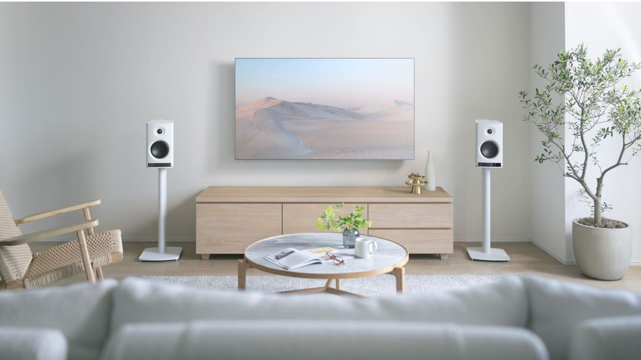 Yamaha NX-70A speakers in white in a well-lit, neutrally decorated room. They are on brackets on either side of a wall-mounted TV.