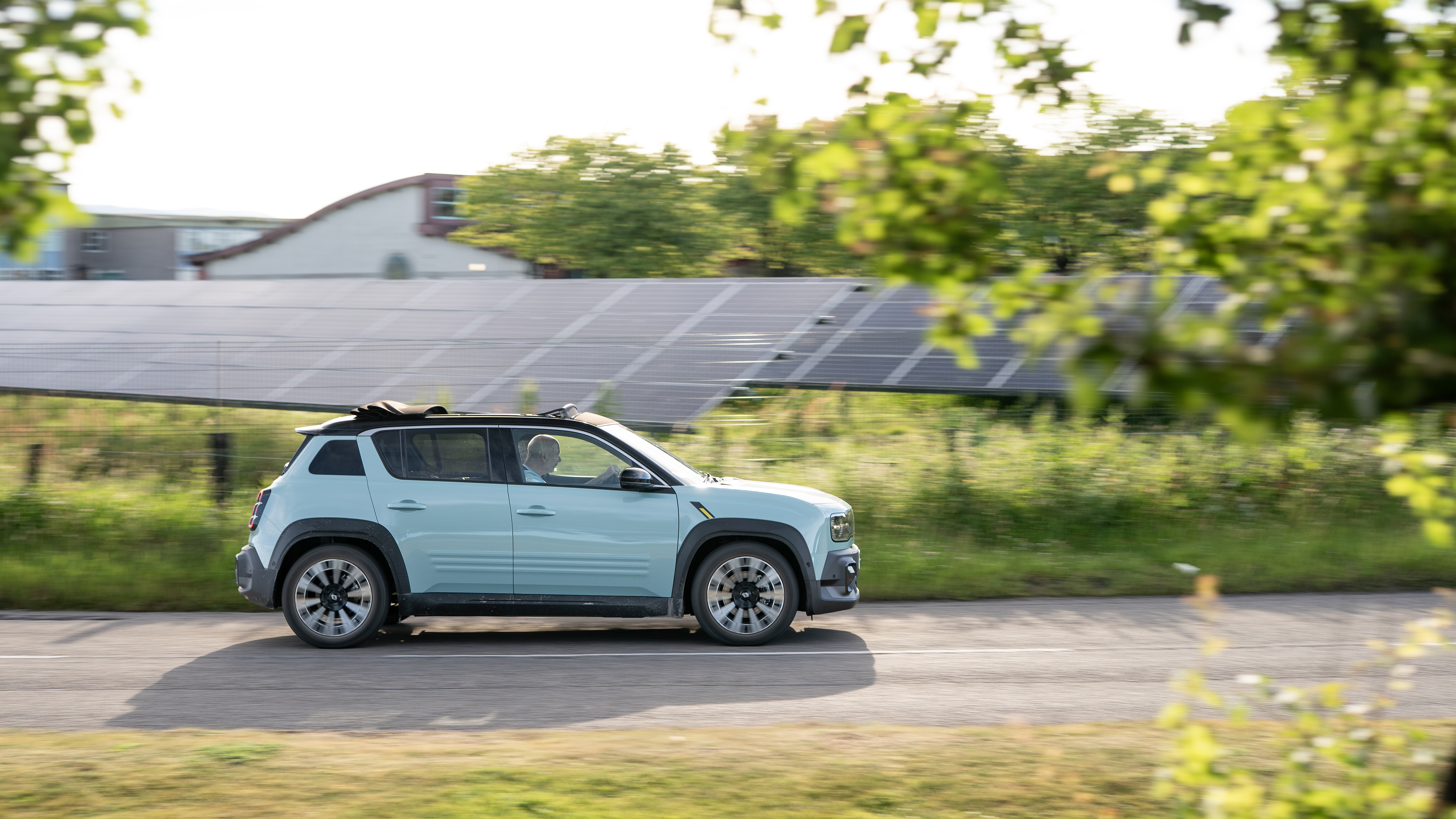 An electric car driving in front of a solar park.