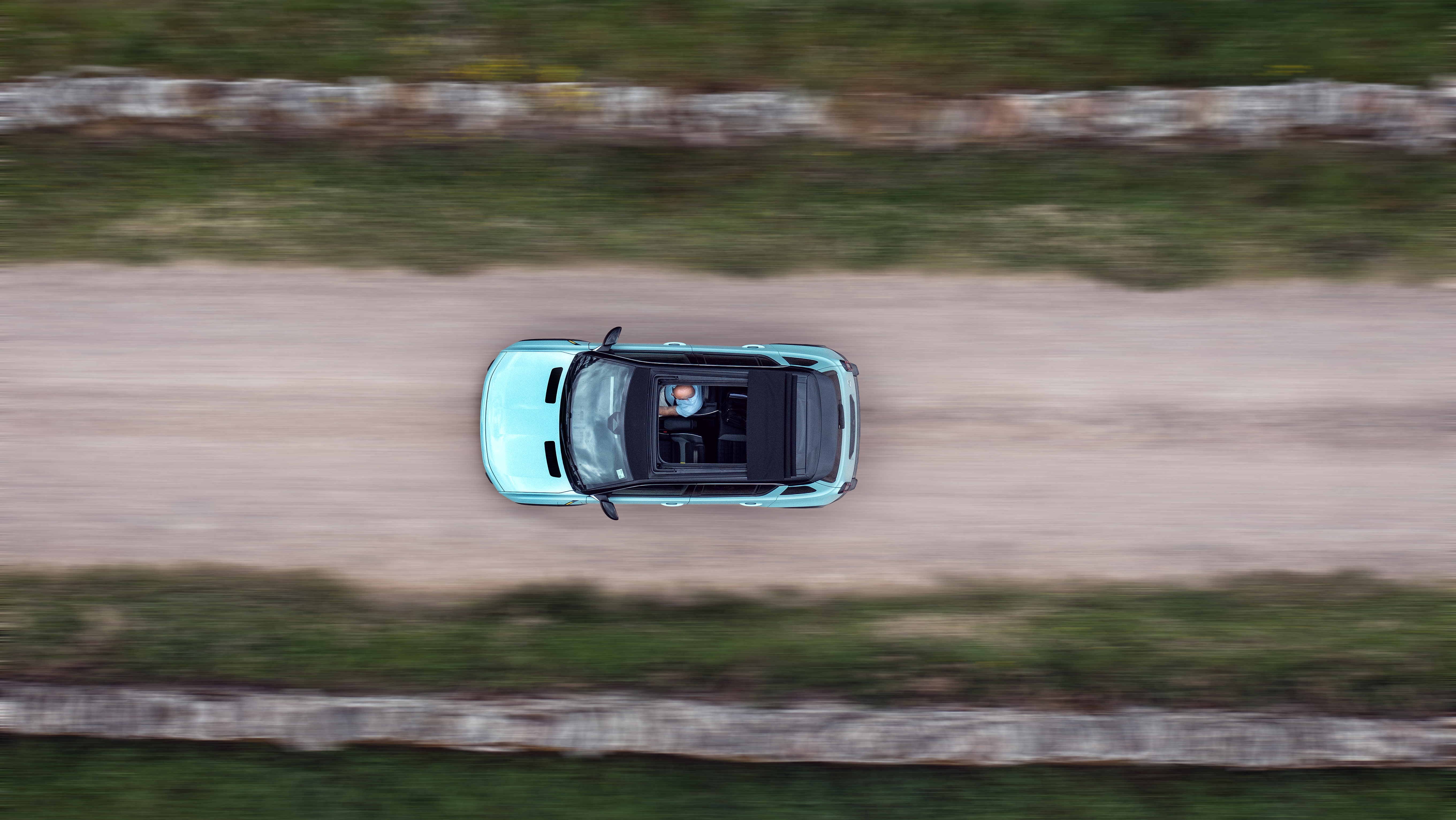 An overhead shot of an electric car driving through the countryside.