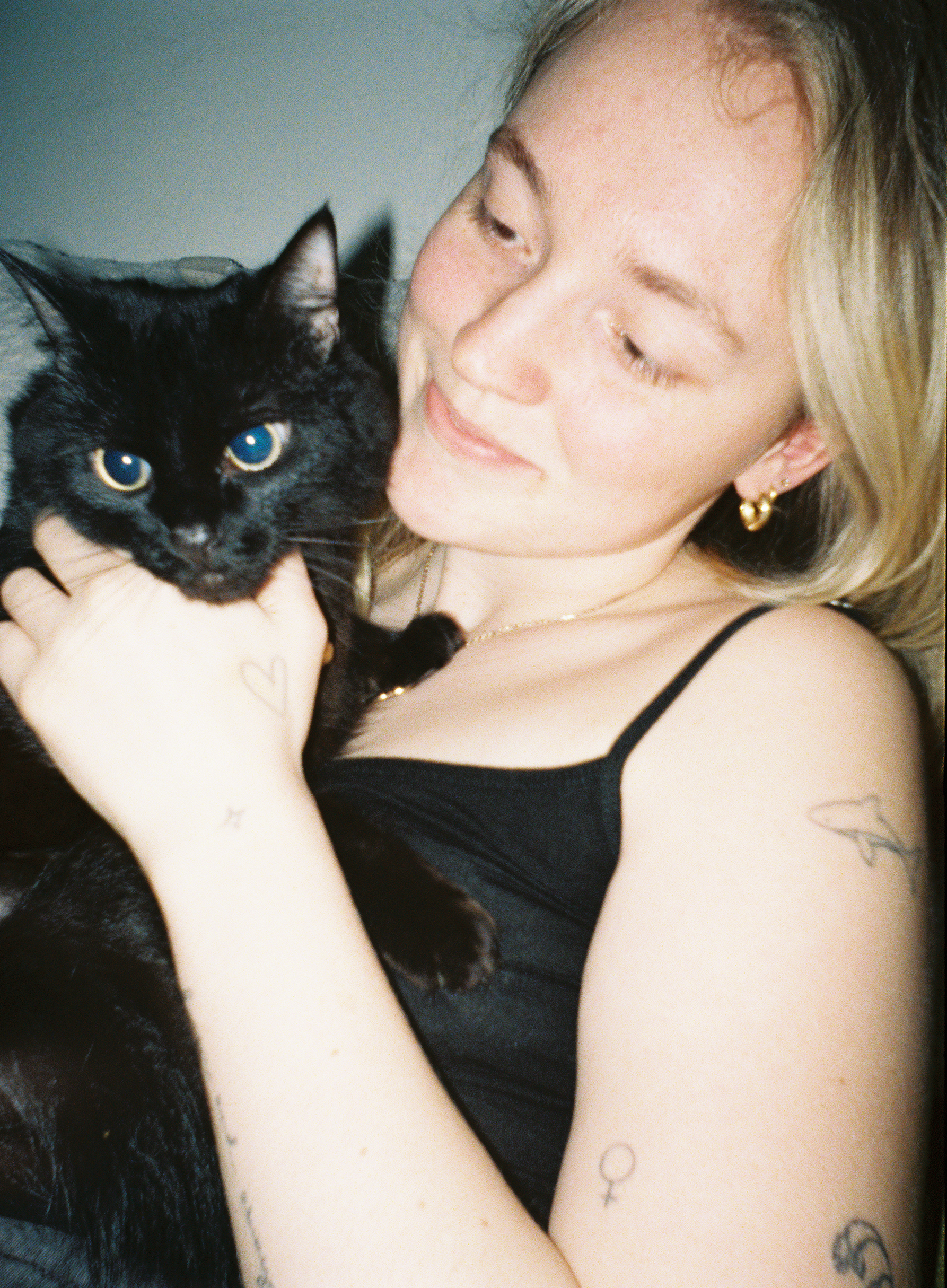 Sample image of Lomography Half-frame Simple Use Rechargeable Film Camera showing a woman holding a black cat, illuminated with flash