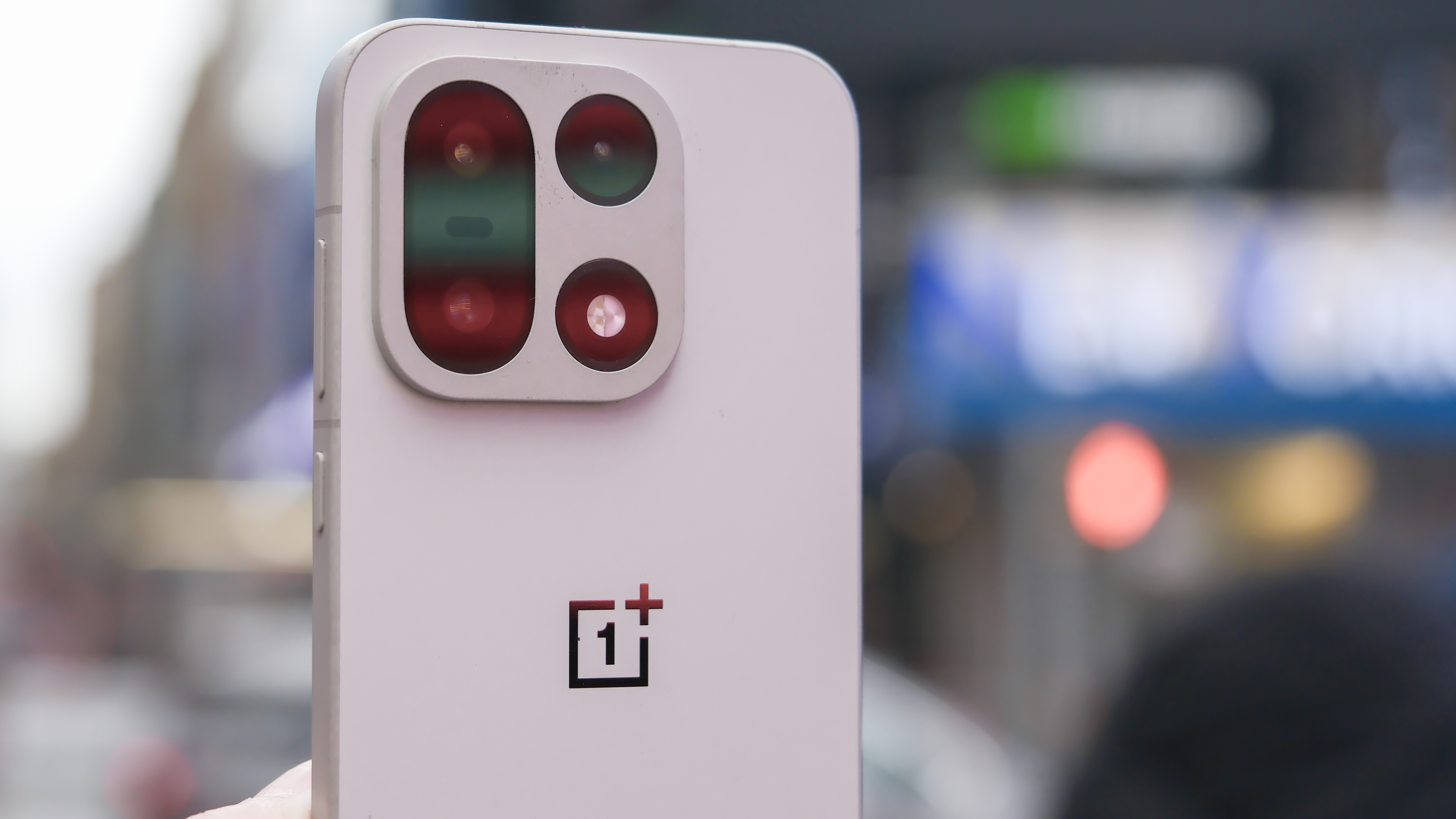OnePlus 15 in Times Square, New York, on the busy street showing the cameras and sides of the phone, plus the home screen panels and settings menus