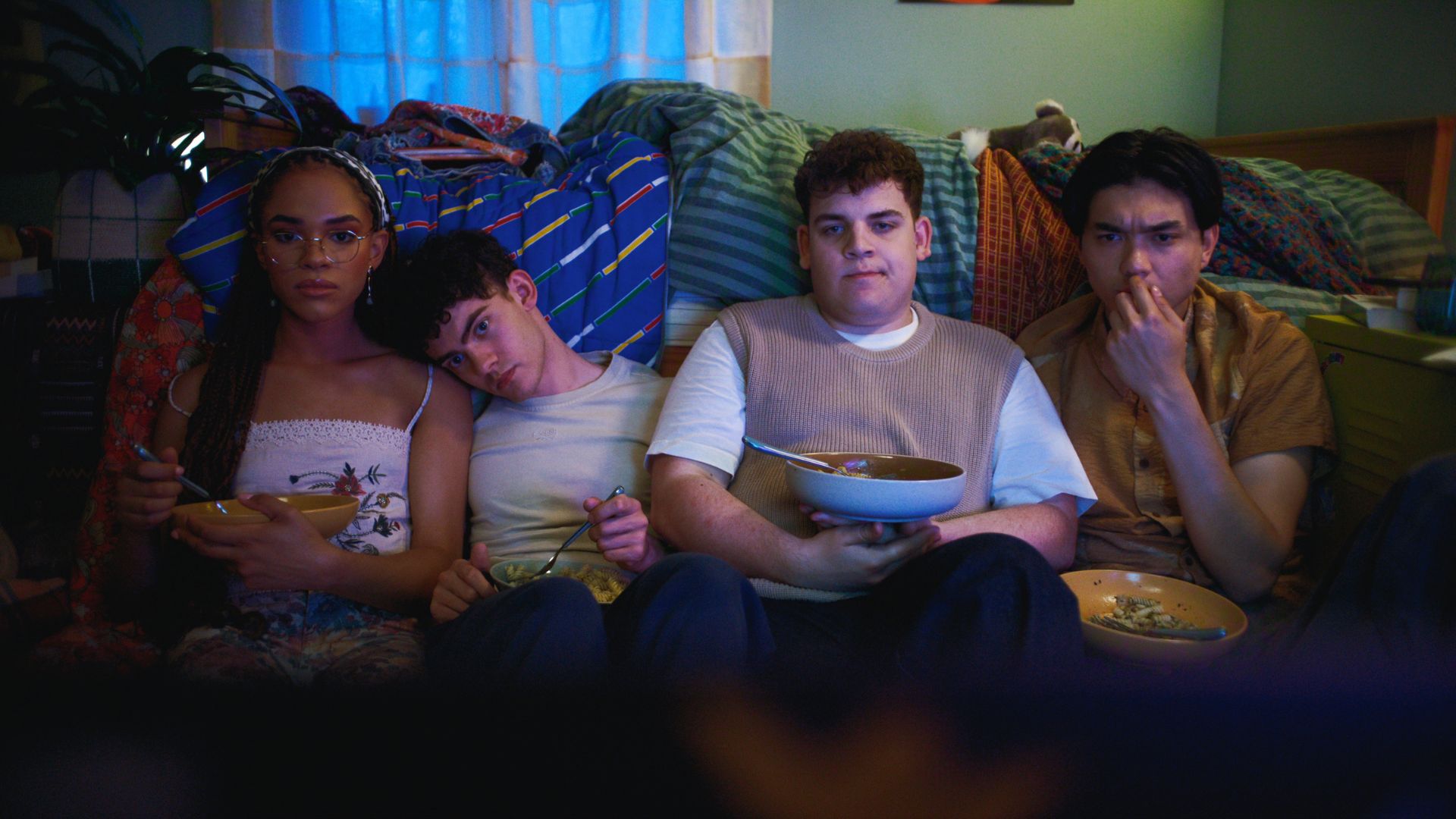 Elle, Charlie, Isaac and Tao sit on the bedroom floor eating pasta.