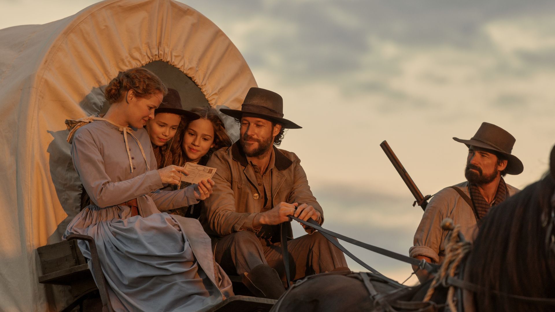 The Ingalls family looks at a letter while sitting in a wagon.
